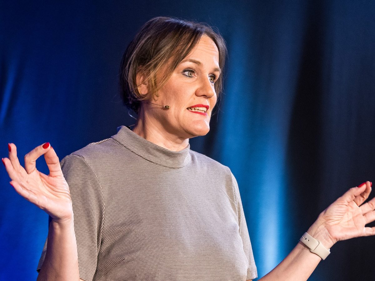 Laura Gintar im Vortrag, Nahaufnahme vor blauer Bühne
