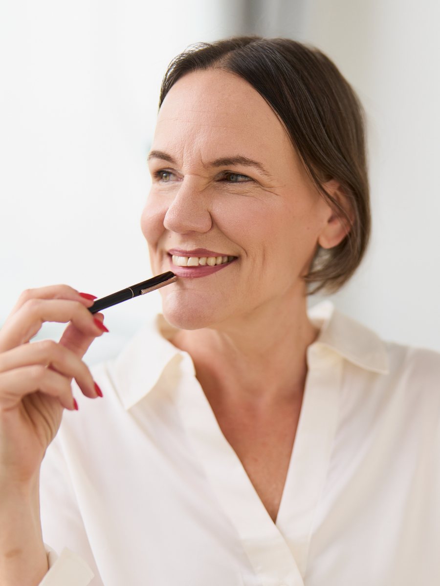 Laura Gintar mit einem Stift am Mund, in Gedanken